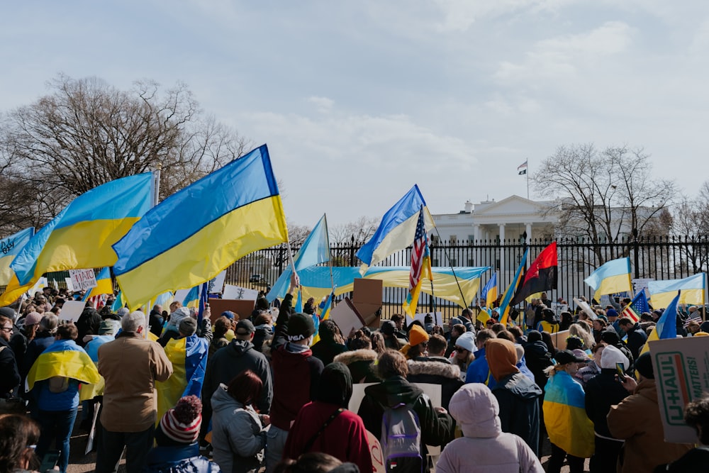 un grand groupe de personnes tenant des drapeaux et des pancartes