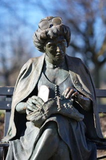 a statue of a woman sitting on a bench