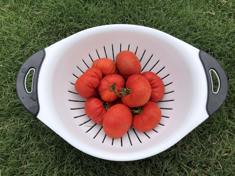 a white bowl filled with lots of ripe tomatoes