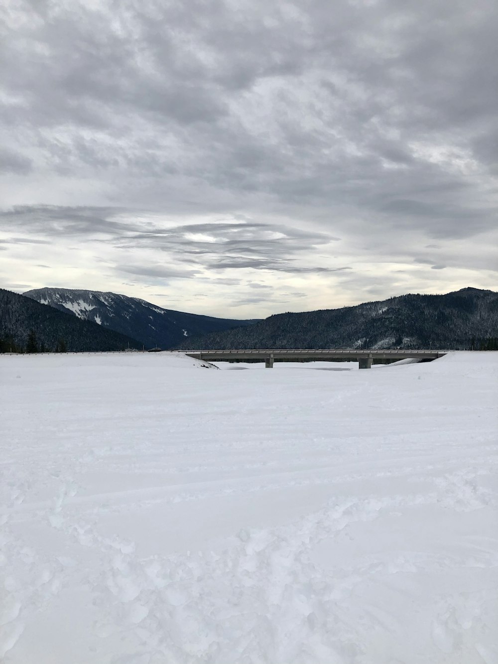 a snow covered field with mountains in the background