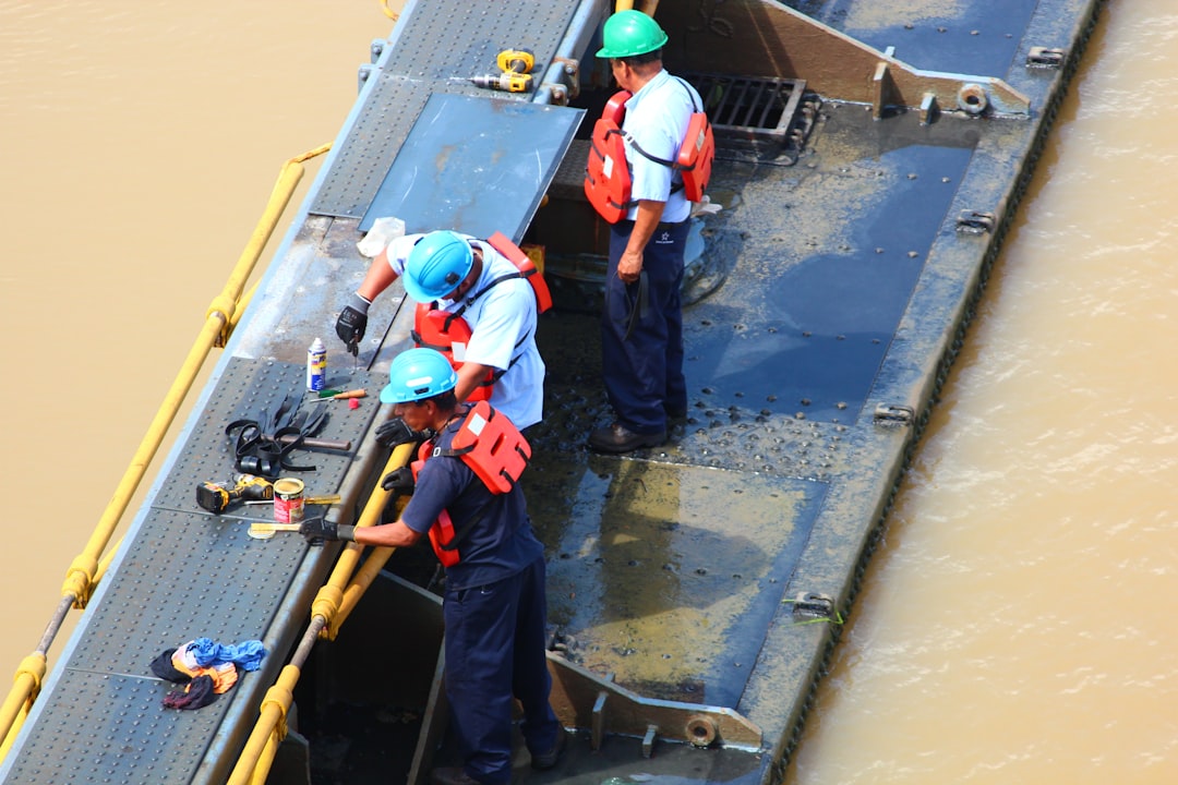 a couple of men standing on top of a boat, Men at work at the Panama Canal