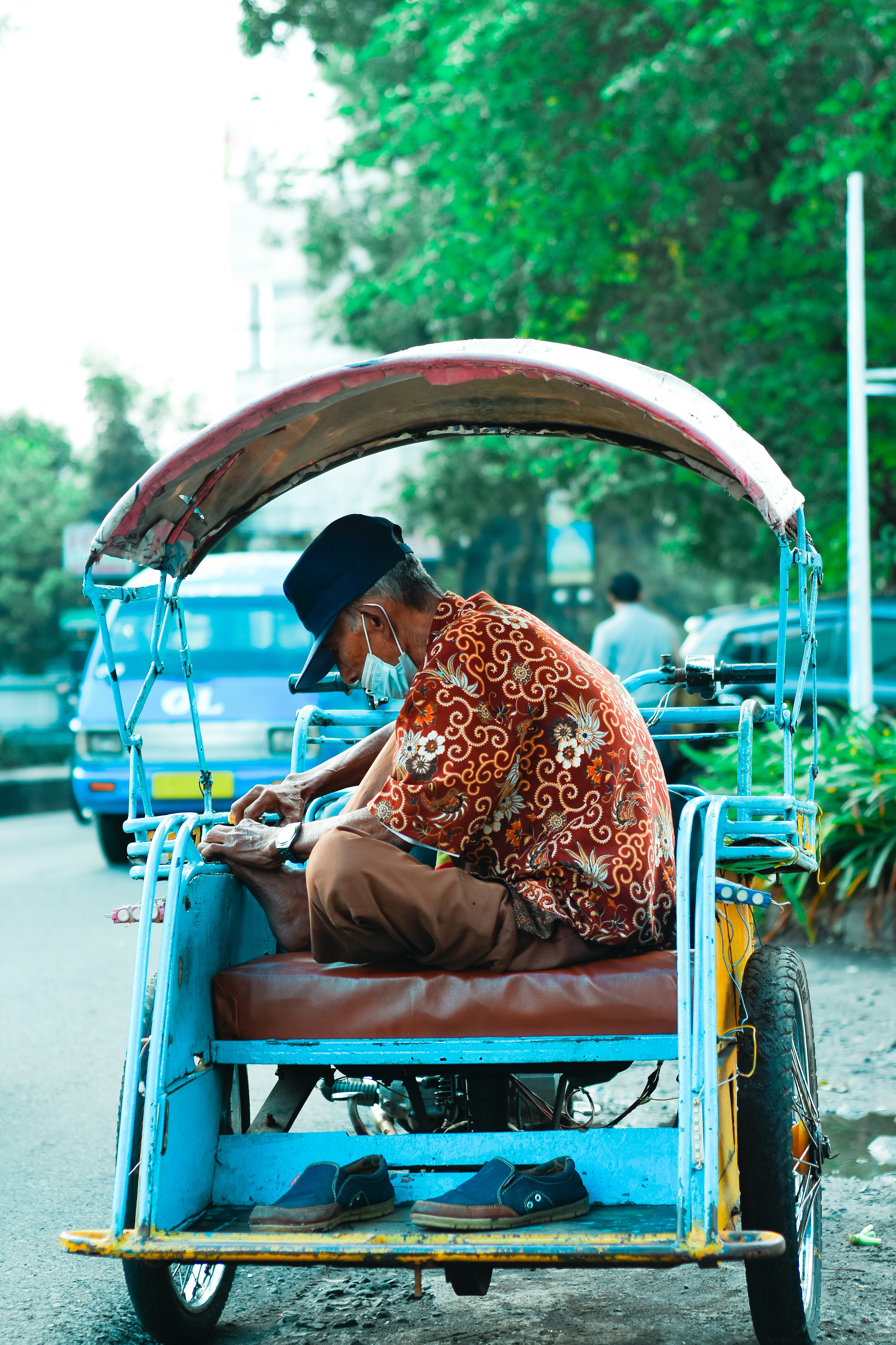 Seorang pria sedang duduk di becak di jalan