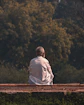 a man sitting on a bench in front of a forest