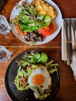 A vibrant, colorful keto meal featuring avocado, eggs, and fresh greens on a rustic wooden table.