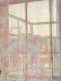 Elegant curtains in soft pink hues gently draping a sunlit window.