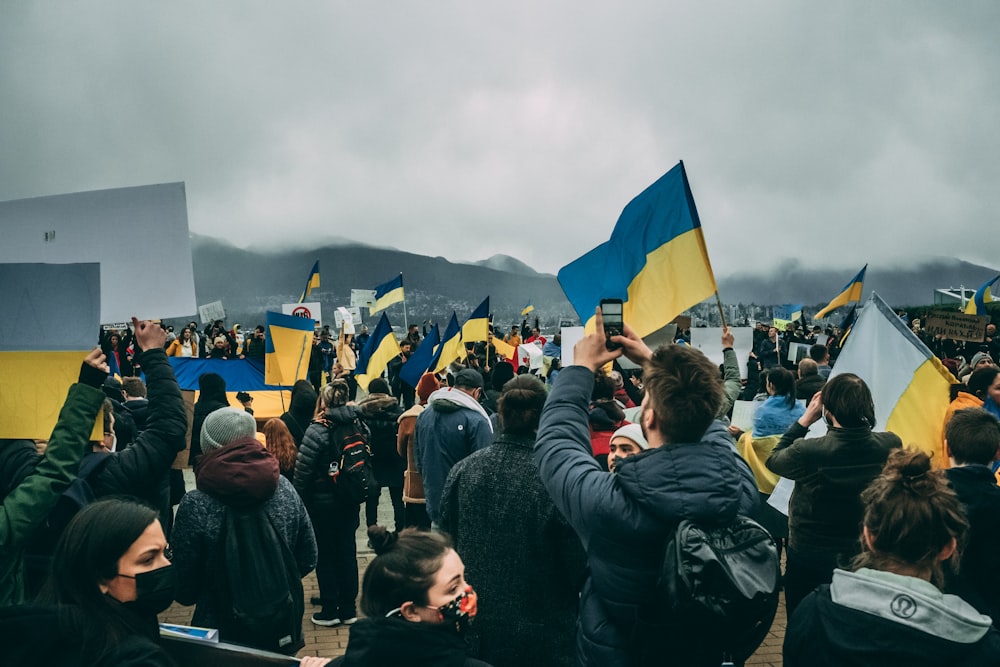 a crowd of people standing around each other holding flags