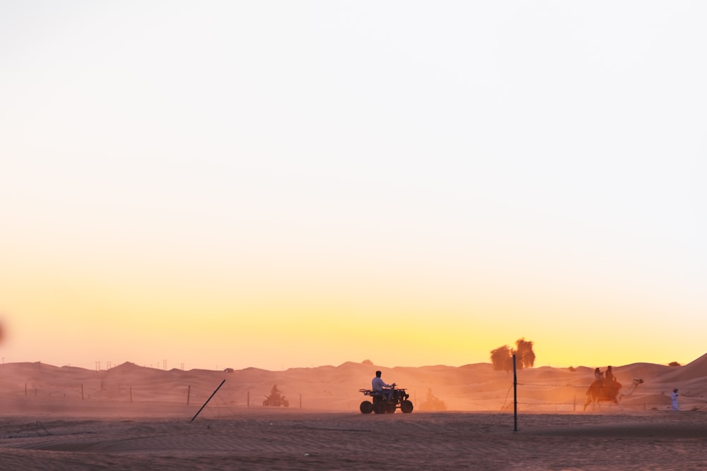 a tractor is driving through the desert at sunset
