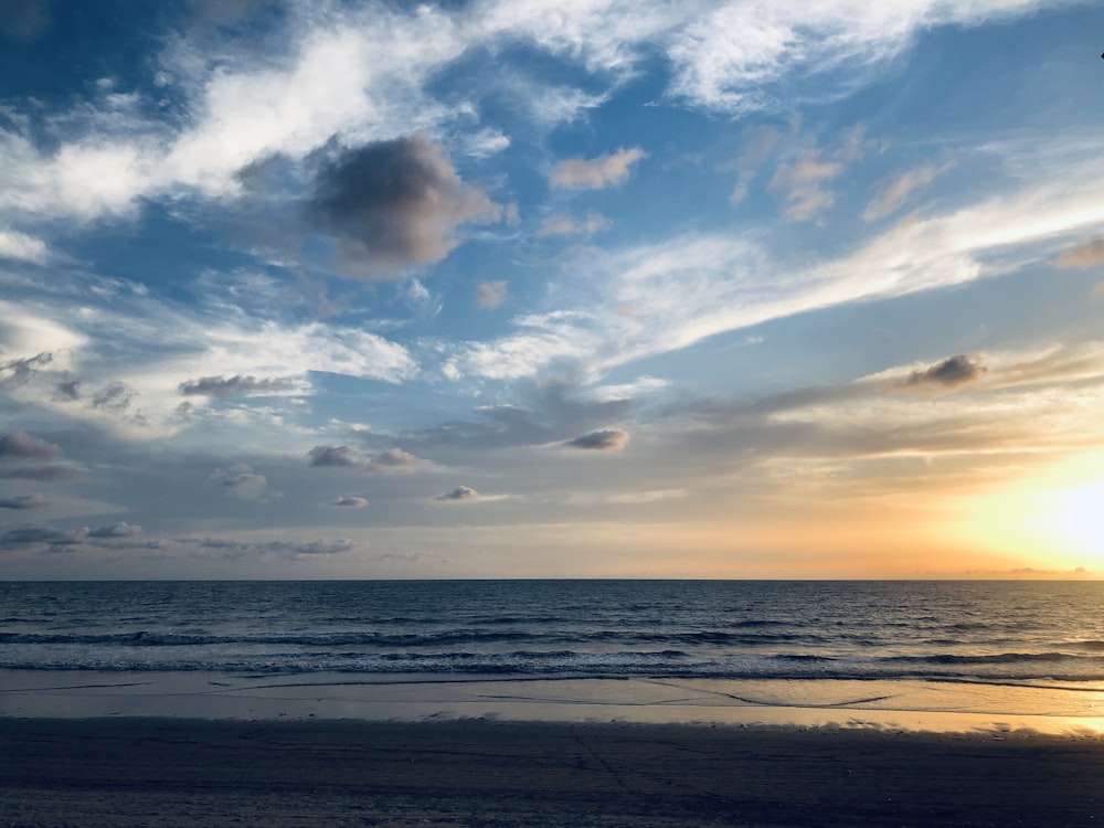 the sun is setting over the ocean on the beach