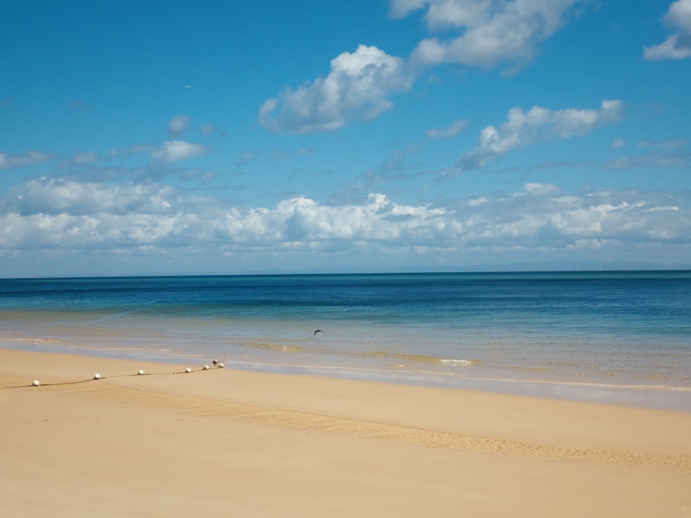 a sandy beach with a blue sky and white clouds