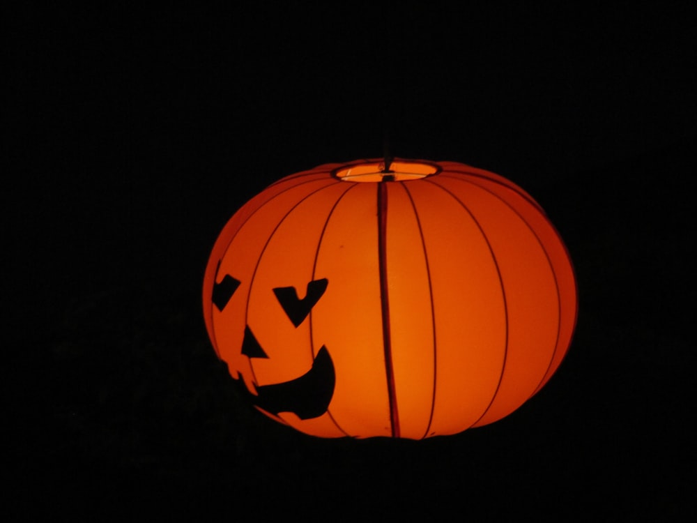 a lit up pumpkin lantern in the dark