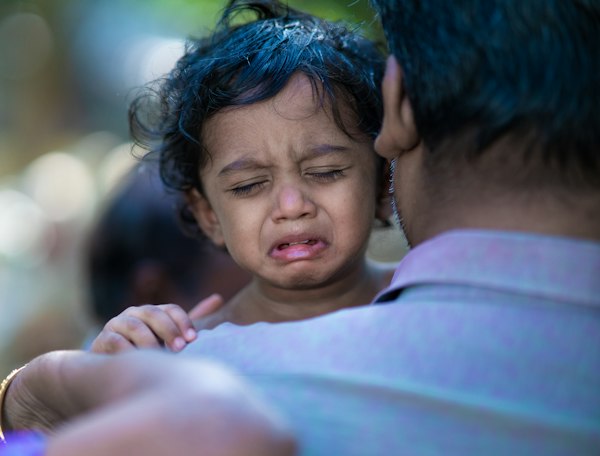 Mother crouching down to talk calmly at eye level with her 3 year old