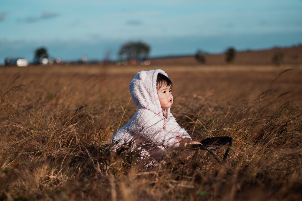 a young child sitting in a field of tall grass
