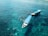 Two boats are floating on clear, turquoise waters. Several people in snorkel gear are swimming around the boats, enjoying the aquatic environment.