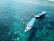 Two boats are floating on clear, turquoise waters. Several people in snorkel gear are swimming around the boats, enjoying the aquatic environment.