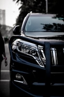 a black suv parked next to a woman walking down a street