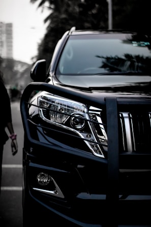 a black suv parked next to a woman walking down a street
