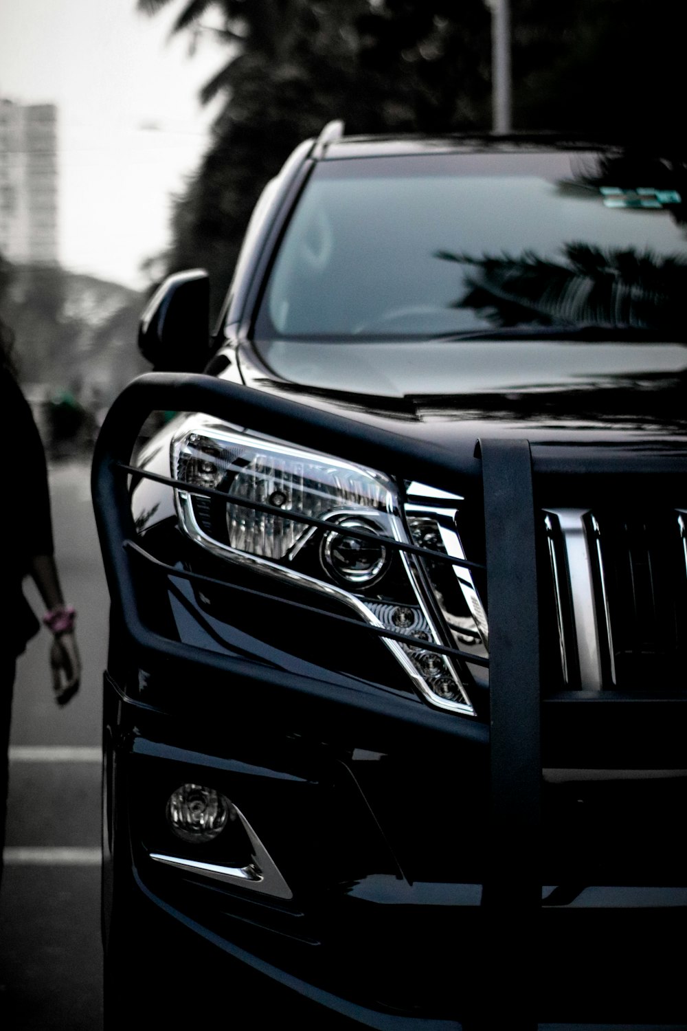 a black suv parked next to a woman walking down a street