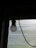 A light bulb is suspended from the ceiling in front of a translucent window that allows some diffuse light to enter. The bulb is connected to a visible black wire, creating a contrast against the soft lighting coming through the window.