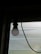 A light bulb is suspended from the ceiling in front of a translucent window that allows some diffuse light to enter. The bulb is connected to a visible black wire, creating a contrast against the soft lighting coming through the window.