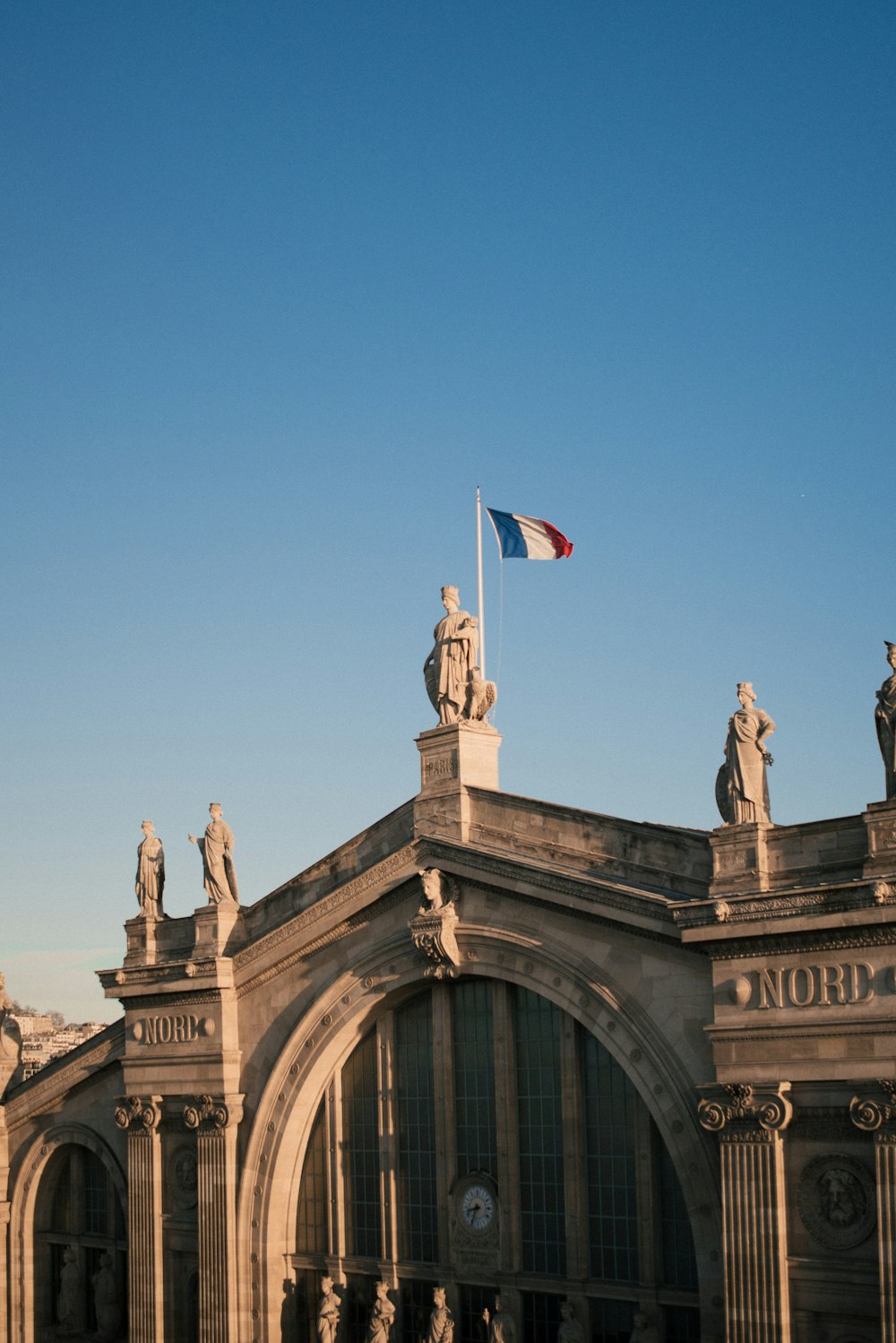 a building with statues and a flag on top of it