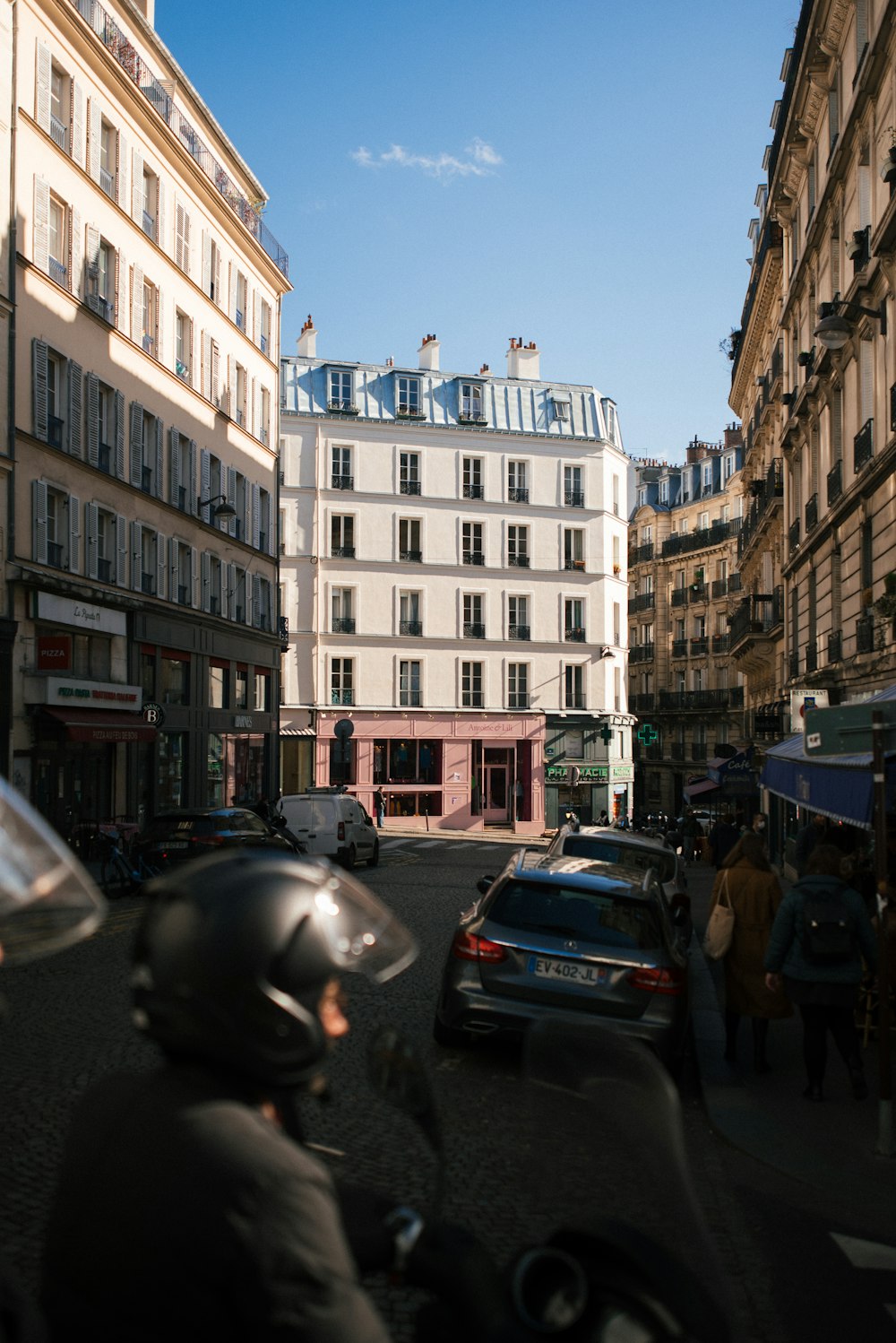 a person riding a motorcycle down a street next to tall buildings