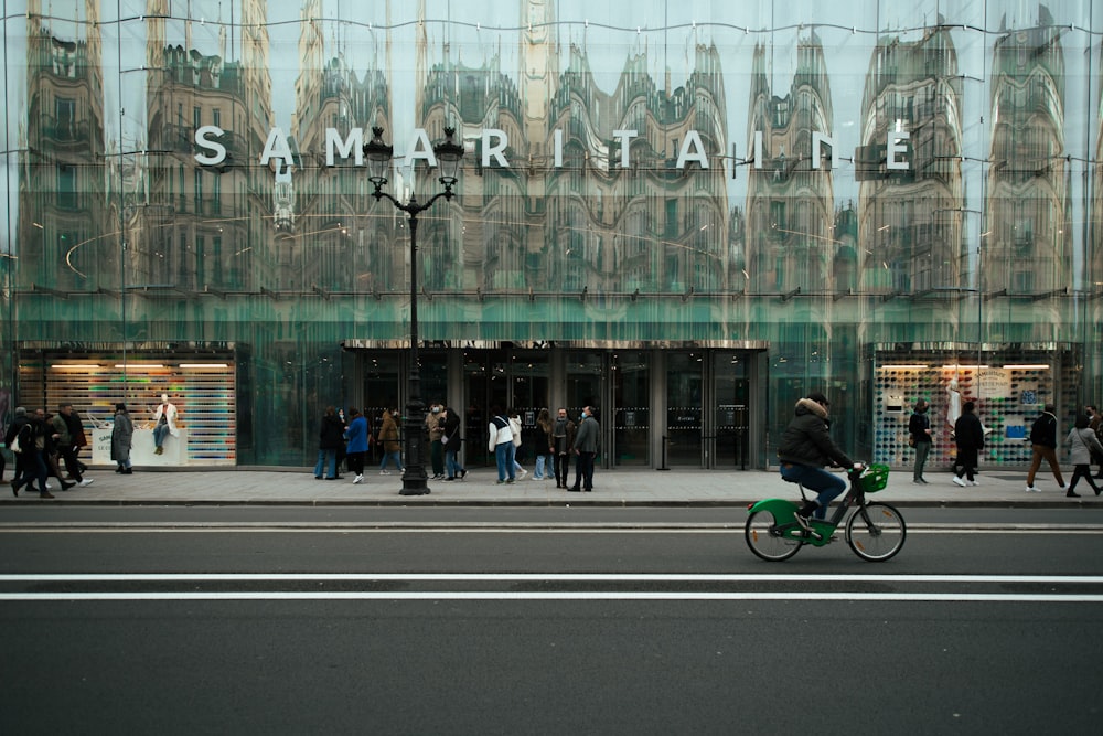 a man riding a bike down a street next to a tall building