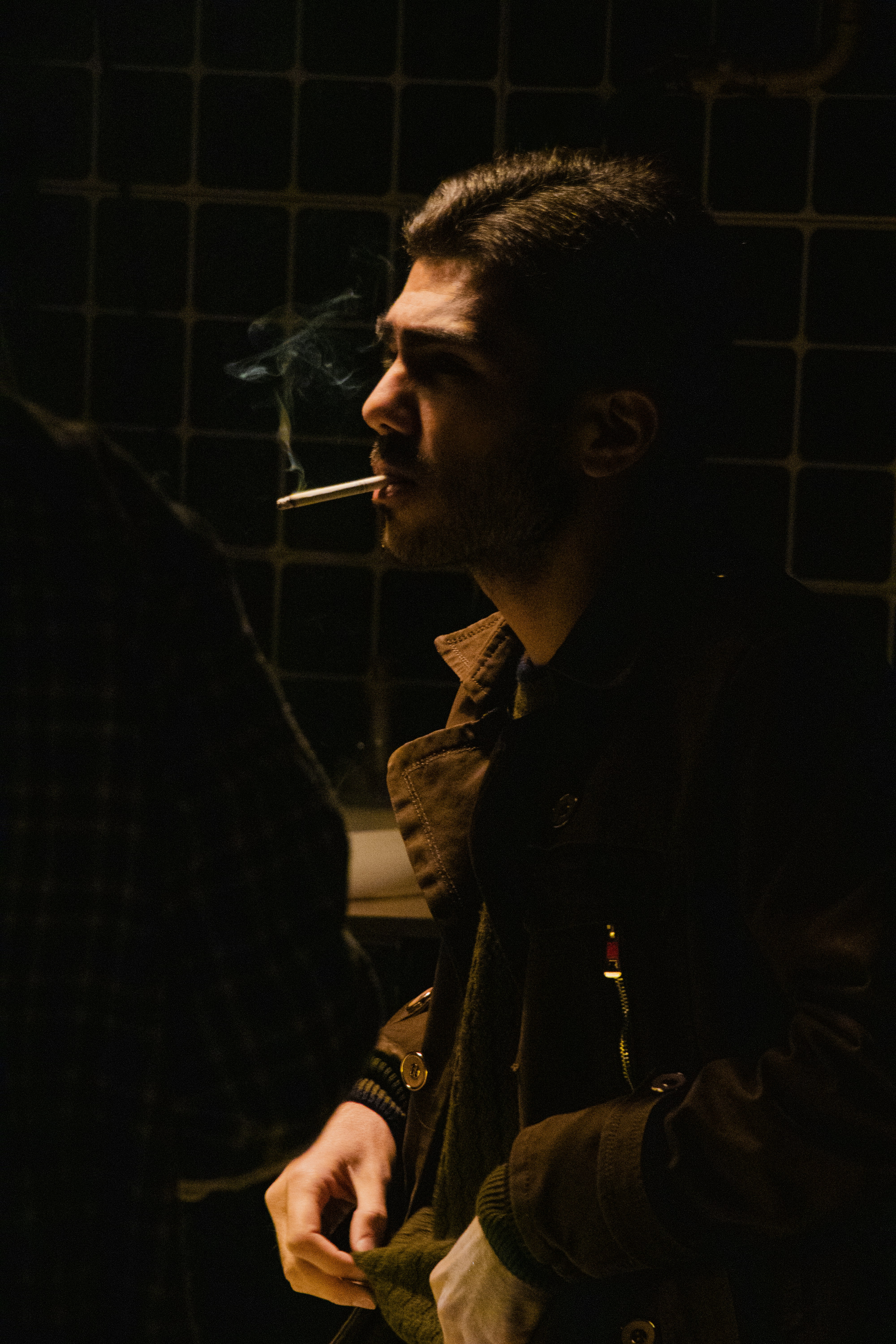 a man smoking a cigarette in a dark room
