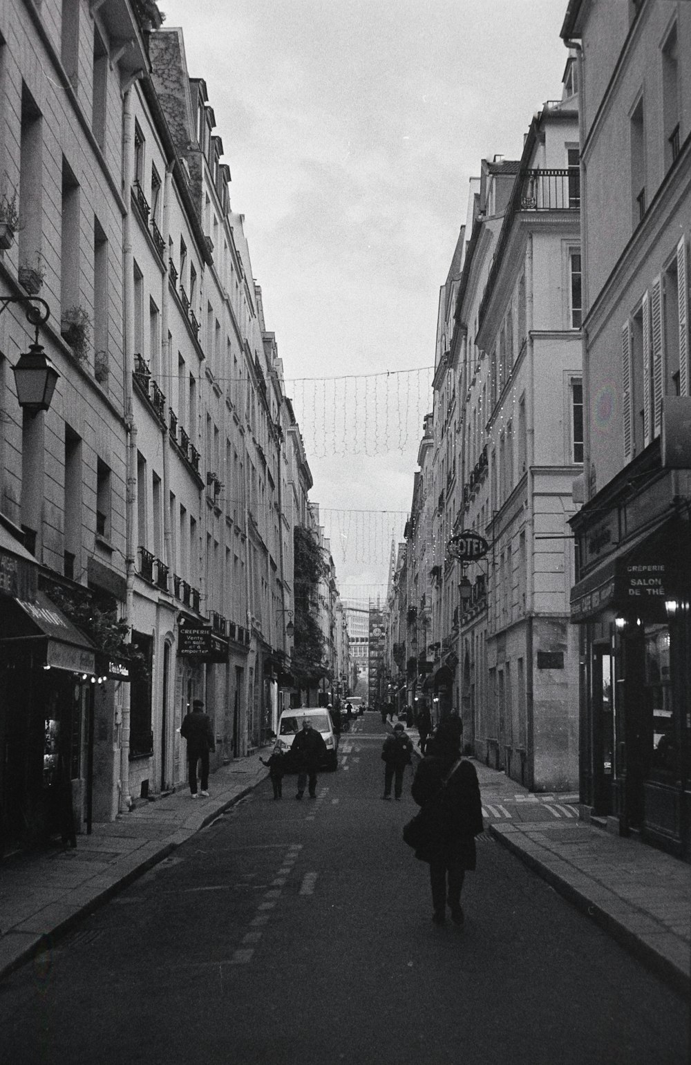 a black and white photo of people walking down a street