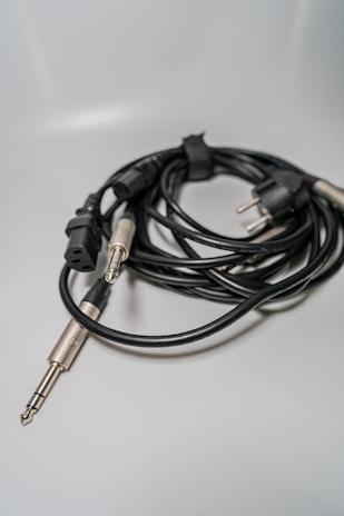 A set of Logic LDNIO audio cables neatly coiled next to a laptop and headphones.