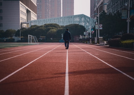 a man walking across a red running track
