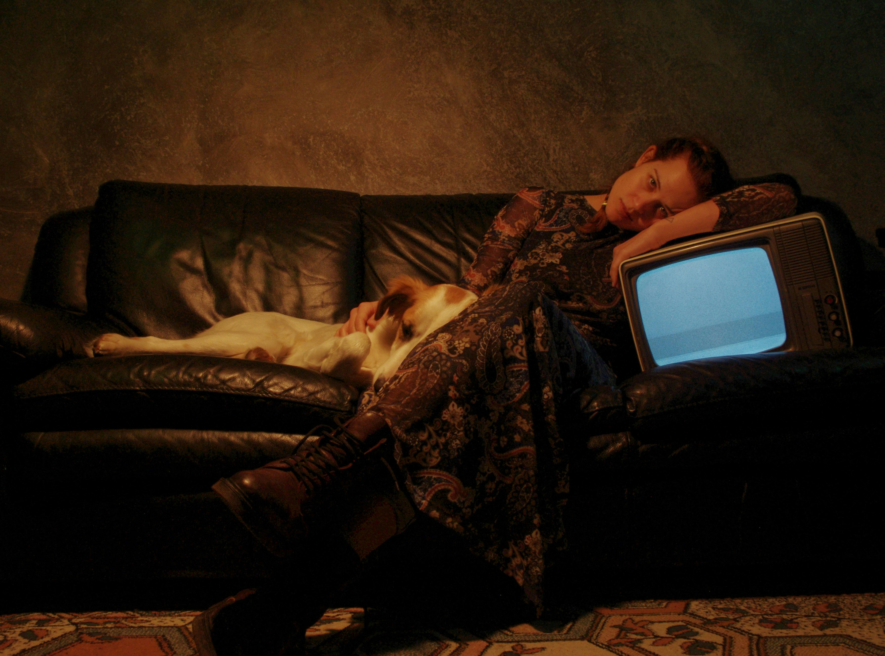 a woman laying on a couch next to a tv