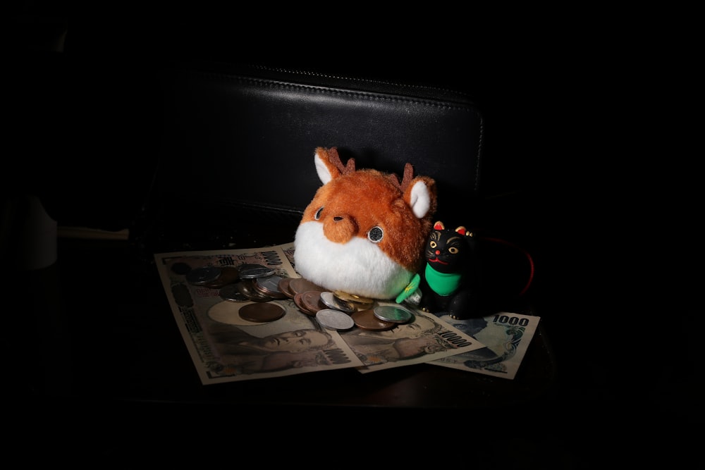 a stuffed animal sitting on top of a pile of money