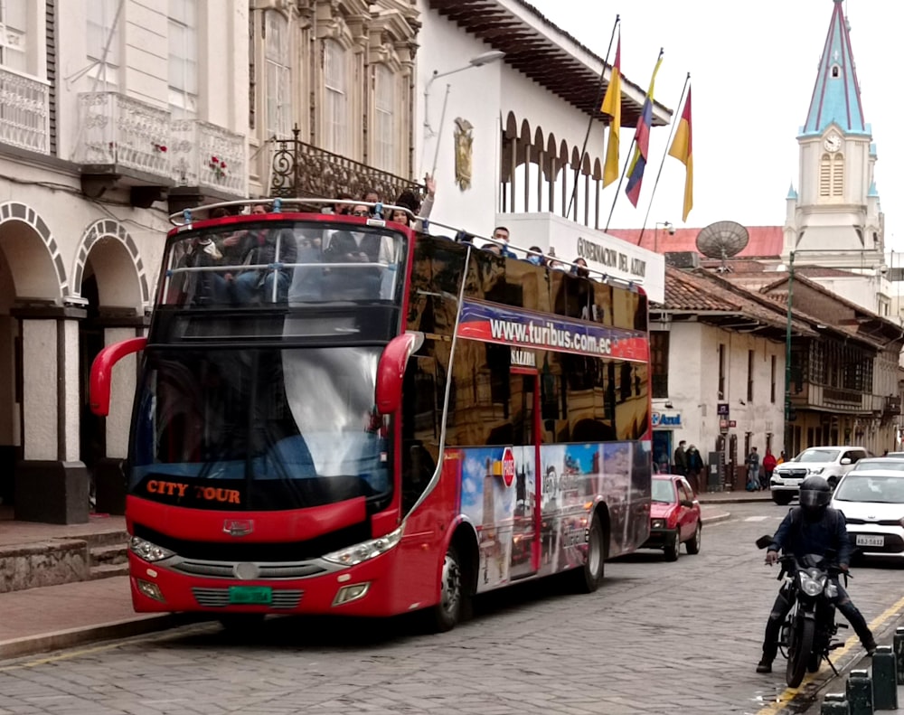 a red double decker bus driving down a street