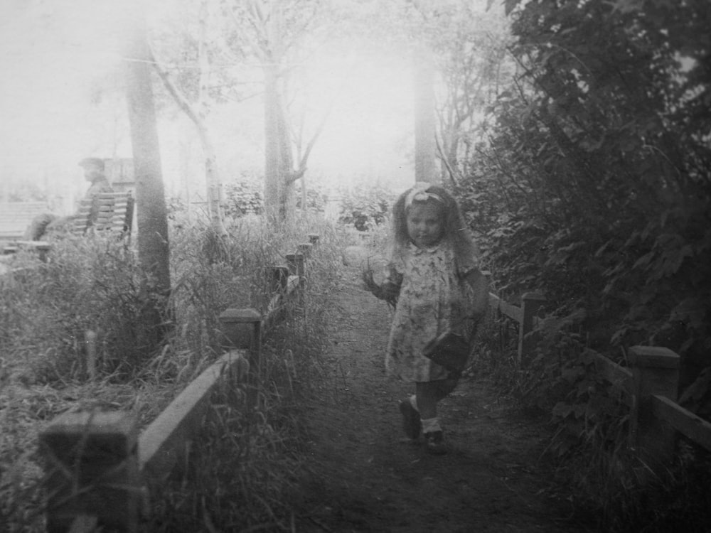 a little girl walking down a path in the woods