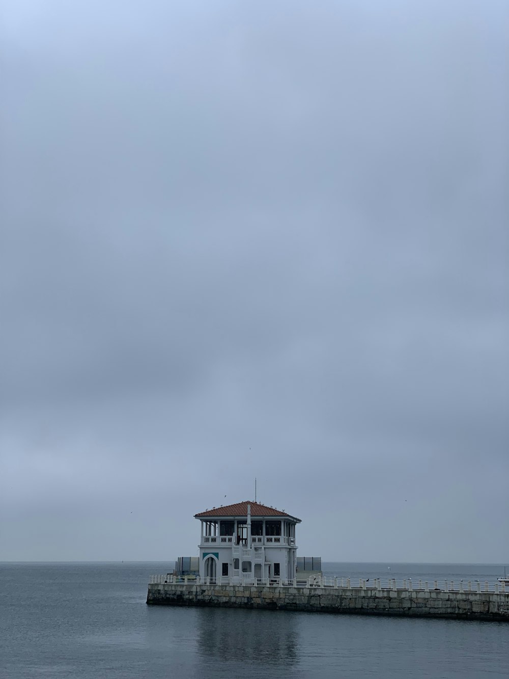 a white house sitting on top of a pier next to the ocean