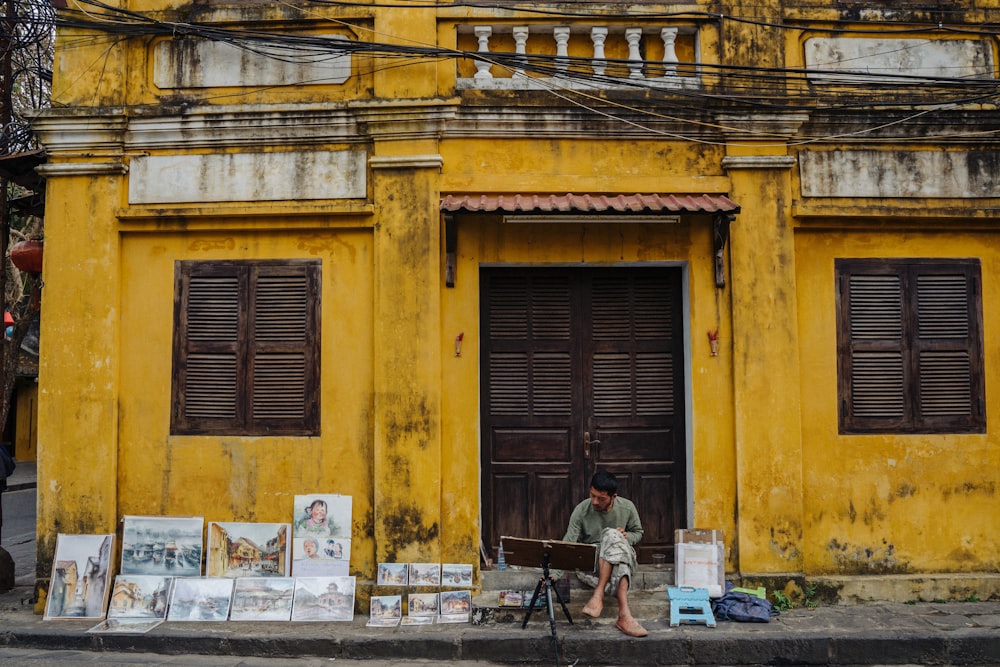 a man sitting on a chair in front of a yellow building