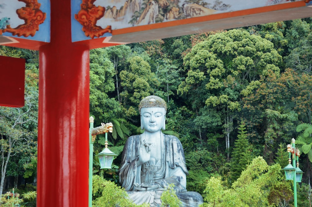 a large buddha statue sitting in the middle of a forest