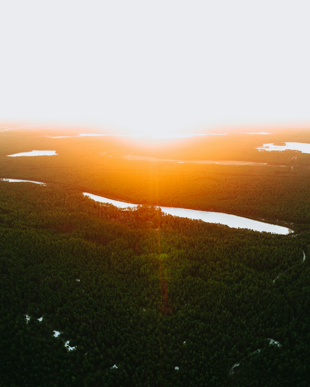 the sun is setting over a lake in the middle of a forest