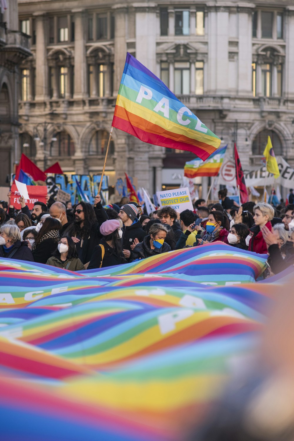 Un grande gruppo di persone che reggono bandiere arcobaleno