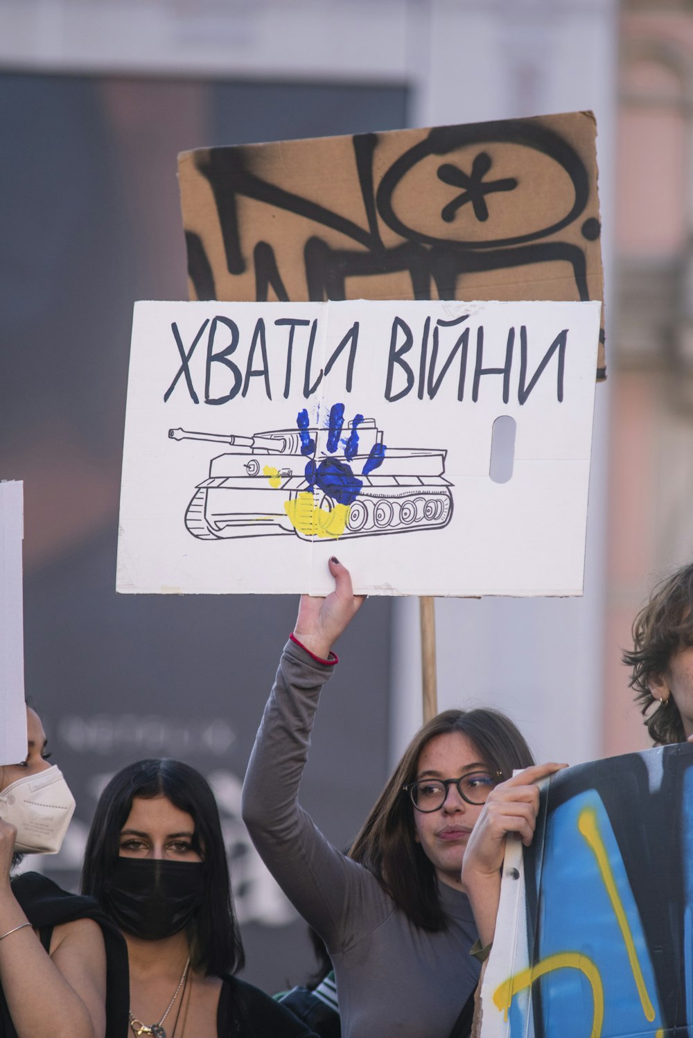 a group of people holding signs and wearing masks