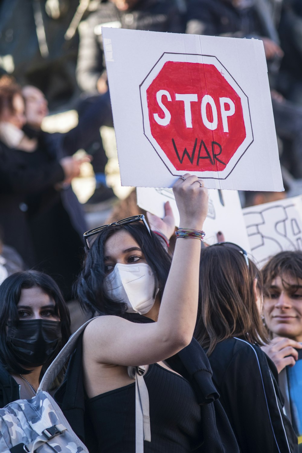 a woman wearing a face mask holding a stop sign