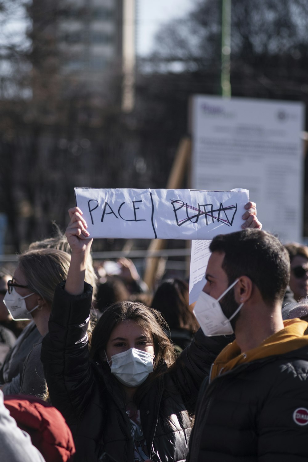 a group of people holding signs and wearing masks