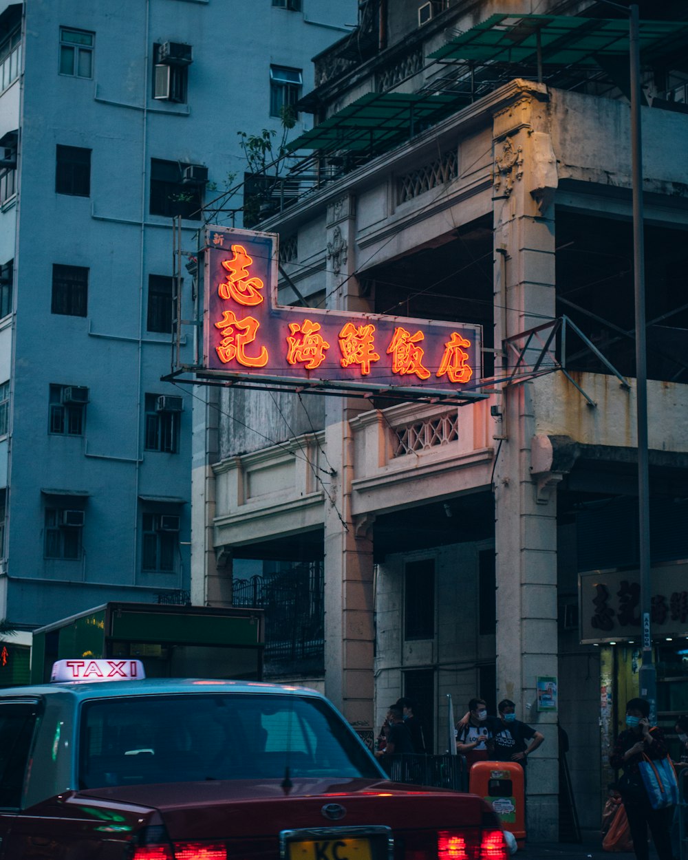 a red car driving down a street next to tall buildings