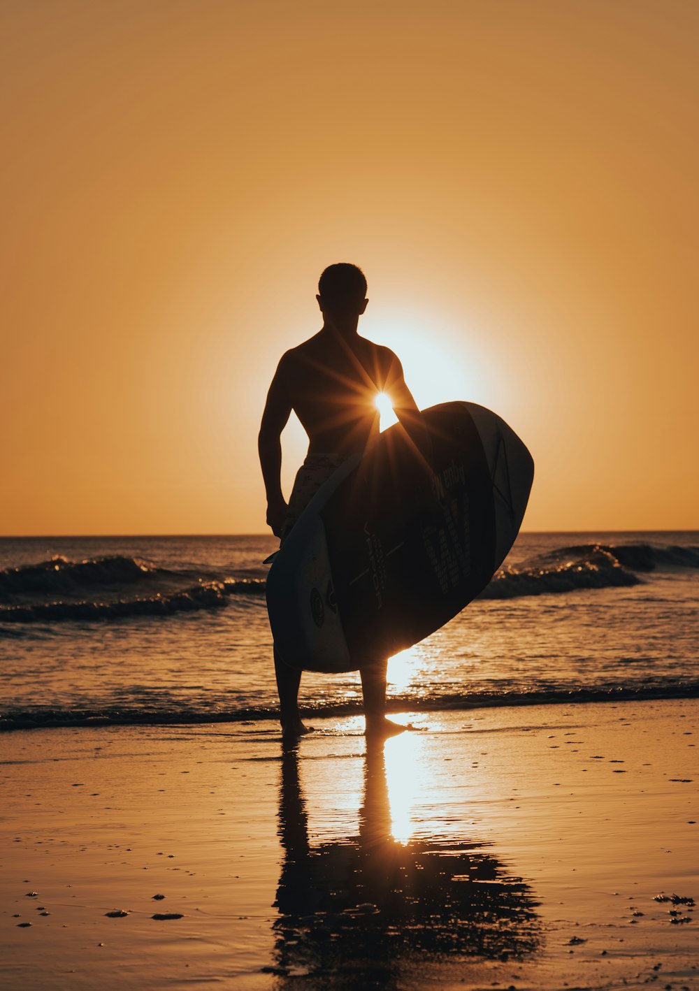 um homem em pé em uma praia segurando uma prancha de surf