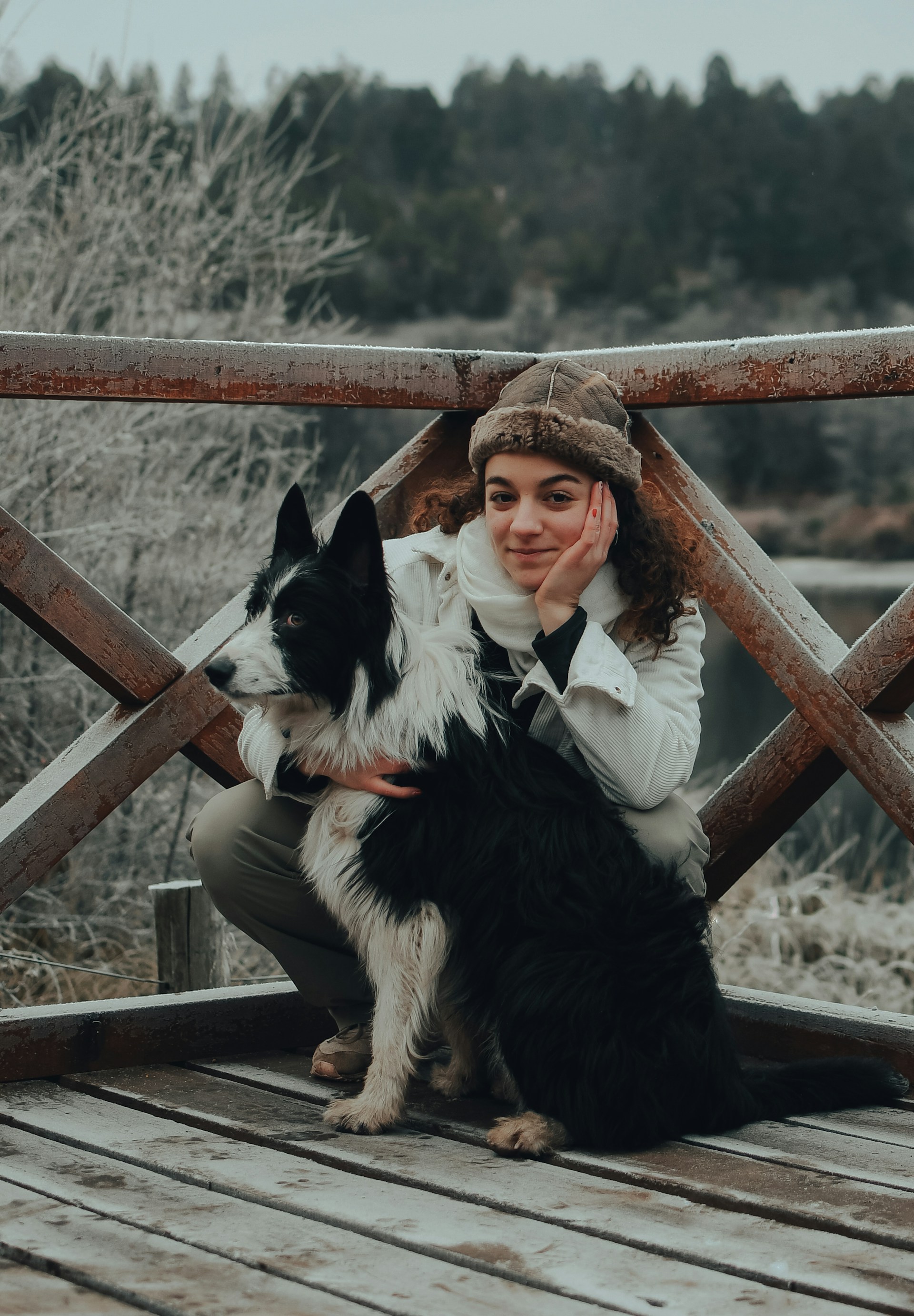 a woman sitting on a wooden bridge with a dog