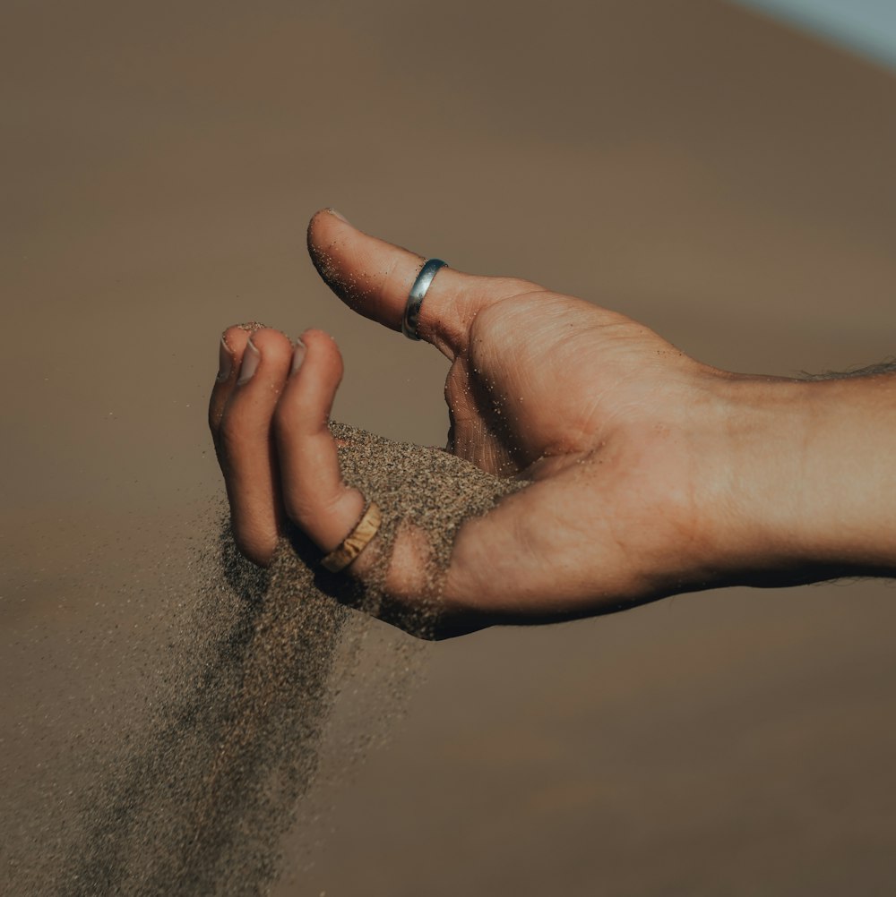 a person holding sand in their hand on the beach