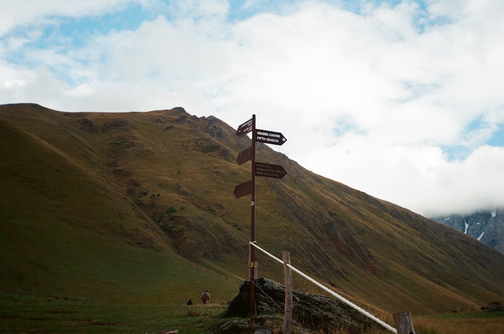 a road sign on a pole in front of a mountain