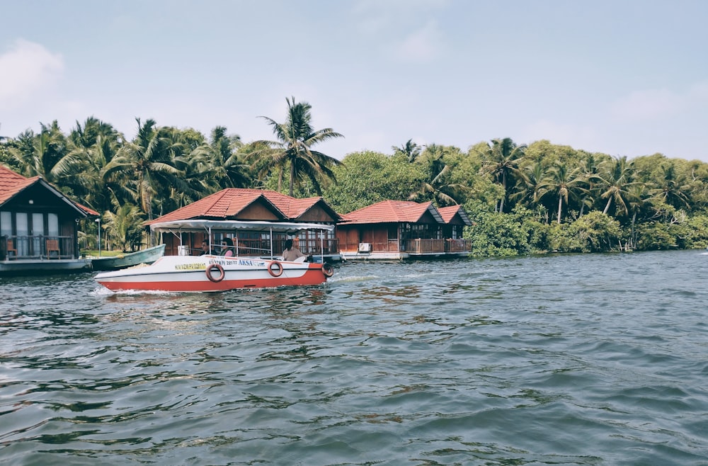 a red and white boat floating on top of a body of water