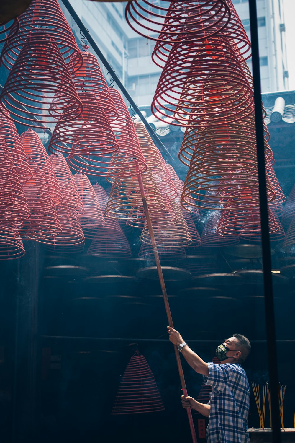 a man holding a stick in front of a bunch of red objects