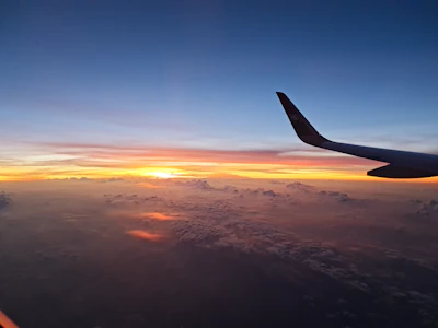 A vibrant sunset view from an airplane window showing the wing and colorful sky.